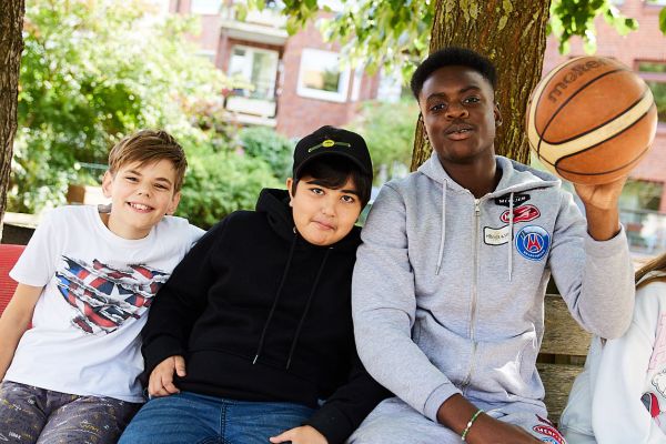 Drei Schüler sitzen auf der Bank und schauen in die Kamera.