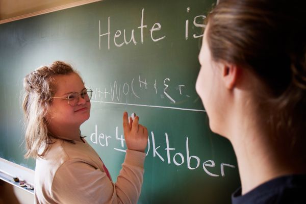 Schülerin schreibt einen Satz an die Tafel.