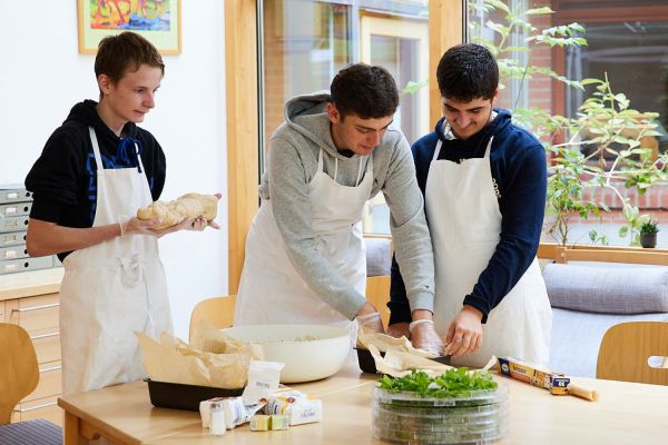 Drei Jungen kneten einen Brotteig.
